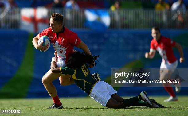 James Davies of Great Britain is tackled by Cecil Afrika of South Africa during the Men's Rugby Sevens semi final match between Great Britain and...