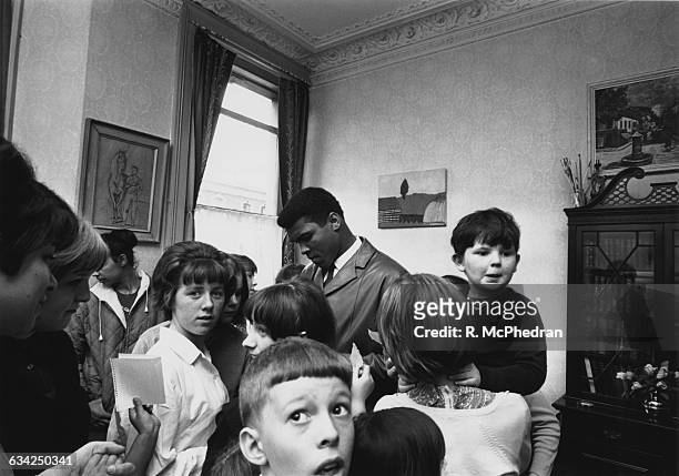 World heavyweight boxing champion Cassius Clay signs autographs during a visit to the London Free School children's play group and families' group at...