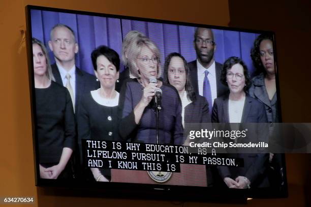 Education Secretary Betsy DeVos appears on a television screen with closed captions while delivering remarks to employees during her first day on the...
