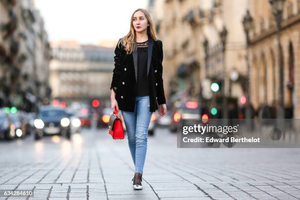 Oceane Grilhe wears Stradivarius silver shoes, Calzedonia fishnet tights, Stradivarius blue denim jeans pants, a Morgan black jacket, a black and red...