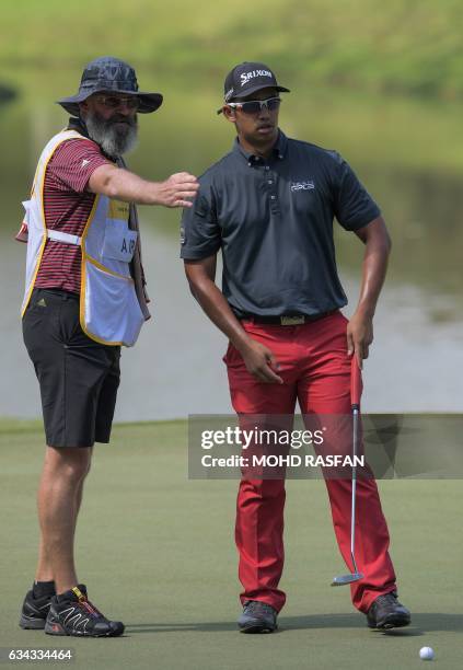 Arie Irawan of Malaysia listens to his caddie before putting during the first round of the 2017 Maybank Malaysia Championship golf tournament at...