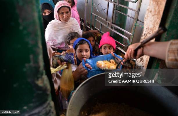 Pakistani residents receive donated food at a distribution point at the Bari Imam shrine in Islamabad on February 9, 2017. - Residents visit shrines...