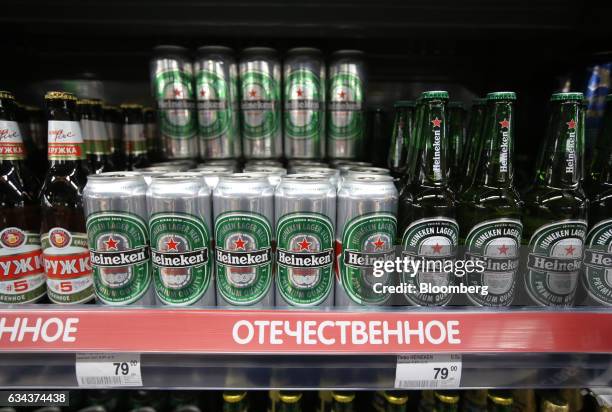 Cans and bottles of Heineken beer, manufactured by Heineken Holding NV, sit on a shelf inside a Perekrestok supermarket, operated by X5 Retail Group...