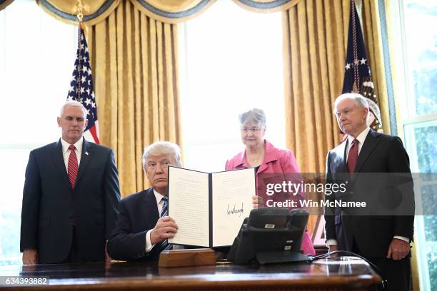 President Donald Trump shows an executive order he signed in the Oval Office of the White House February 9, 2017 in Washington, DC. Prior to signing...