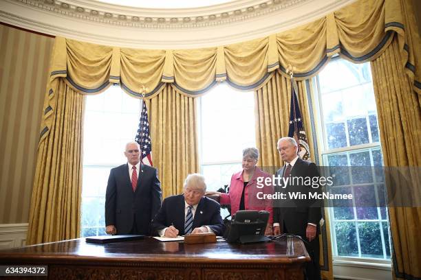 President Donald Trump signs an executive order in the Oval Office of the White House February 9, 2017 in Washington, DC. Prior to signing the three...