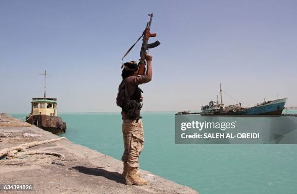 Member of the pro-government forces raises his weapon in the port of the western Yemeni coastal town of Mokha as they advance in a bid to try to...