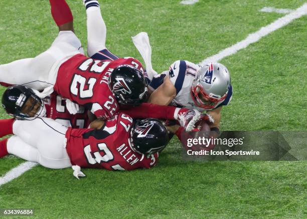 New England Patriots wide receiver Julian Edelman holds on to the ball in spite of being tackled byAtlanta Falcons strong safety Keanu Neal and...