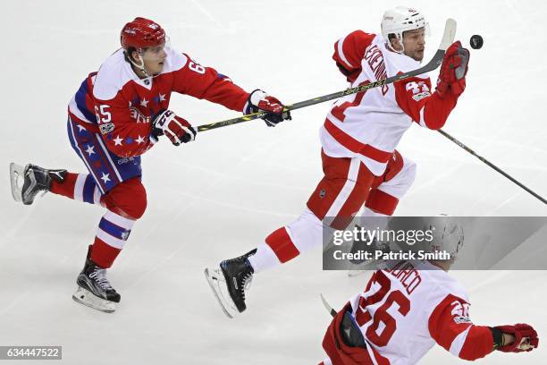 Luke Glendening of the Detroit Red Wings pulls in a loose puck with his hand as he is defended by Andre Burakovsky of the Washington Capitals during...