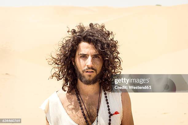 portrait of man with beard and curly hair in the desert - asian man long hair stock pictures, royalty-free photos & images