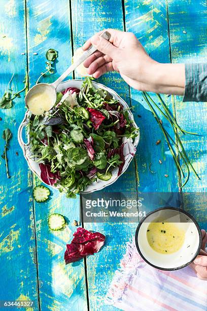 spring salad of baby spinach, herbs, arugula and lettuce, arranging dressing of yogurt, olive oil, honey and lemon - fresh baby spinach stock-fotos und bilder
