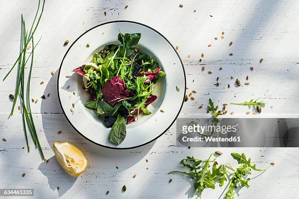 spring salad of baby spinach, herbs, arugula and lettuce on plate, lemon - lettuce fotografías e imágenes de stock