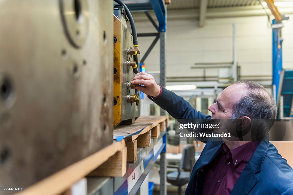 Man examining machine block in storehouse