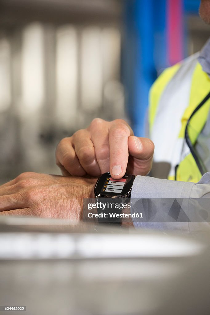Man using smartwatch in industrial plant