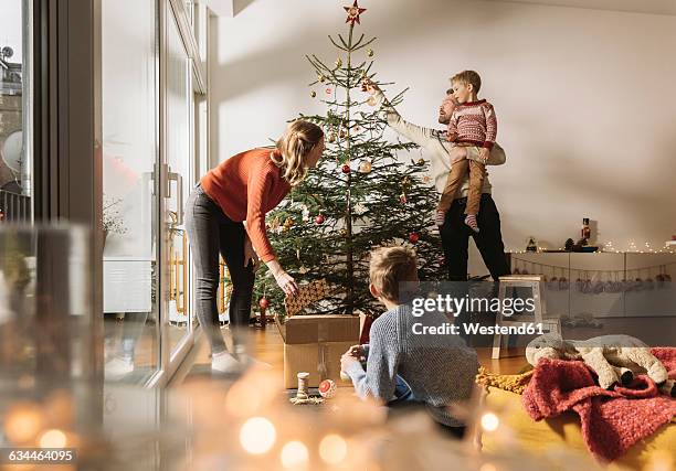 family decorating christmas tree - papa noel stockfoto's en -beelden