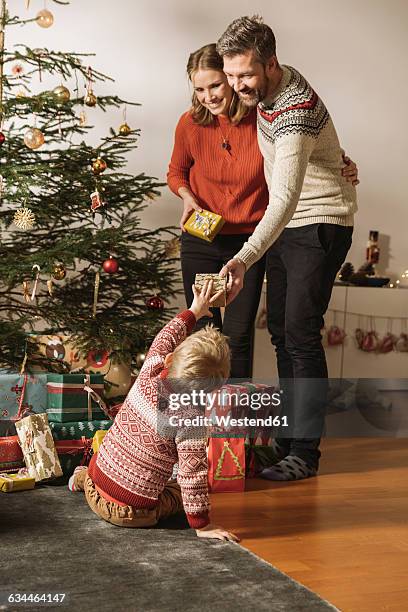 parents giving christmas gifts to little child - gift lounge stock-fotos und bilder