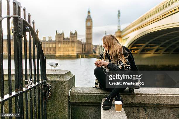 uk, london, young woman taking a snack near westminster bridge - city of westminster london 個照片及圖片檔