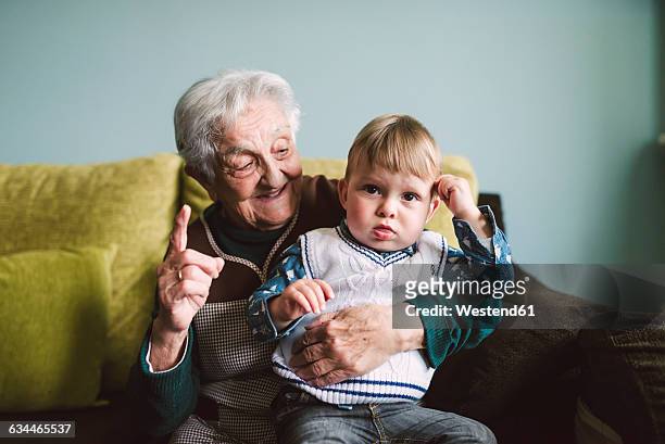 old woman and her great-grandson sitting on the couch - great grandmother photos et images de collection