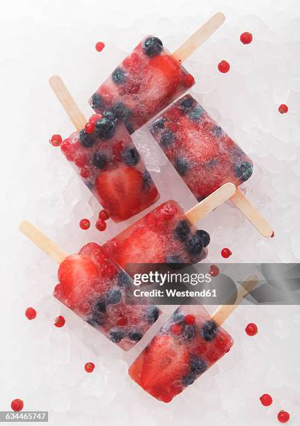 fruit ice lollies with fresh berries - strawberry ice cube studio stock-fotos und bilder