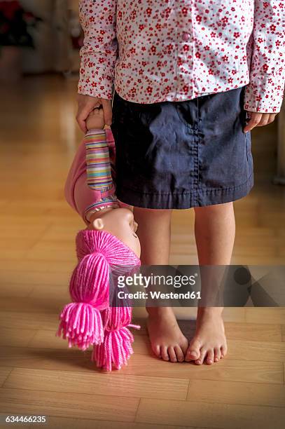 low section of girl standing on wooden floor holding a doll - child abuse stock pictures, royalty-free photos & images