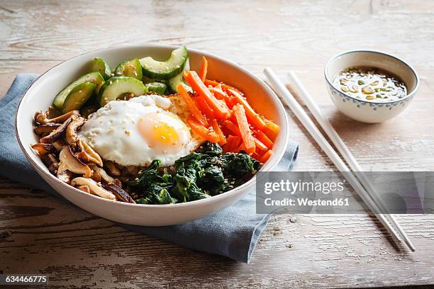 vegetarian korean rice bowl with mushroom, spinach, cucumber, carrot and fried egg - korean food stock pictures, royalty-free photos & images