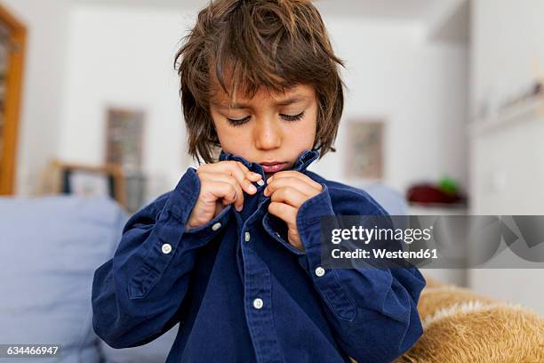 little boy buttoning his shirt - vestir se fotografías e imágenes de stock