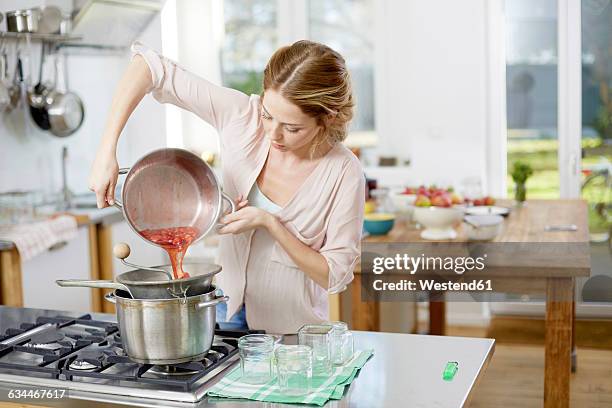 young woman making jam in kitchen - fruit pot stock pictures, royalty-free photos & images