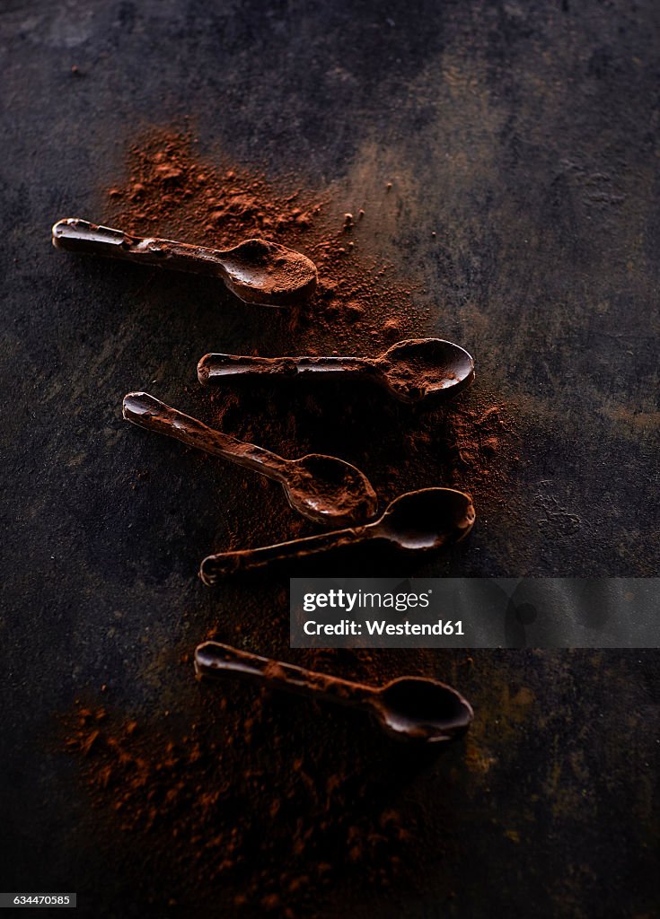 Five chocolate spoons sprinkled with cocoa