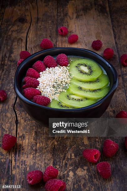 bowl of kiwi apple rocket smoothie with chia seed, popped amarant, kiwi slices and raspberries - amarant stock pictures, royalty-free photos & images