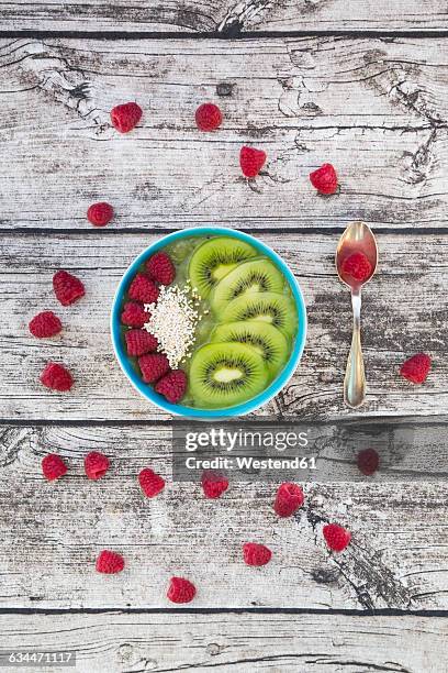 bowl of kiwi apple rocket smoothie with chia seed, popped amarant, kiwi slices and raspberries - amarant stock pictures, royalty-free photos & images