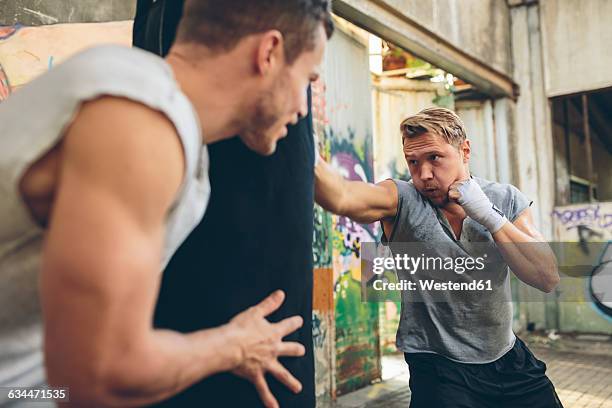 boxer exercising at punch bag - boxing coach stock pictures, royalty-free photos & images