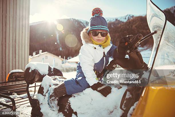 italy, val venosta, slingia, boy with sunglasses sitting on a snowmobile - snowmobiling stock-fotos und bilder