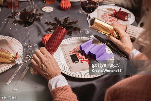 senior woman holding two ends of christmas crackers - arrastrar mueble fotografías e imágenes de stock