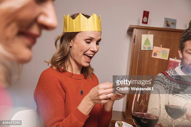 woman with paper crown reading a poem from her christmas cracker - christmas cracker stock pictures, royalty-free photos & images