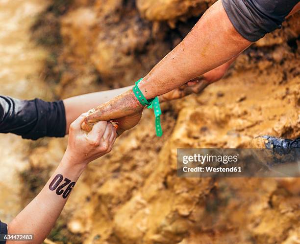 participants in extreme obstacle race helping each other - mud runner stock pictures, royalty-free photos & images