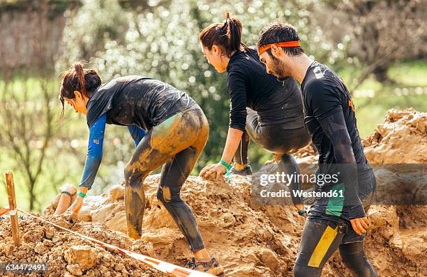 participants in extreme obstacle race, running through mud - mud run stock-fotos und bilder