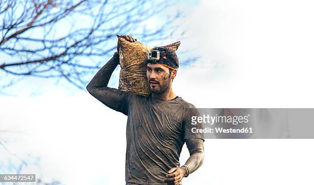 participant in extreme obstacle race carrying sandbags - sandbag stock-fotos und bilder