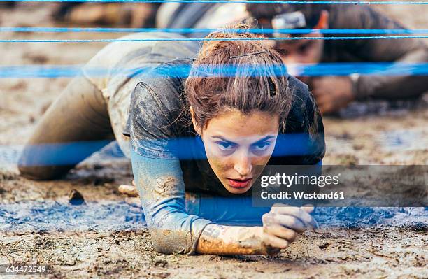 participants in extreme obstacle race crawling under electric wire - gijón fotografías e imágenes de stock