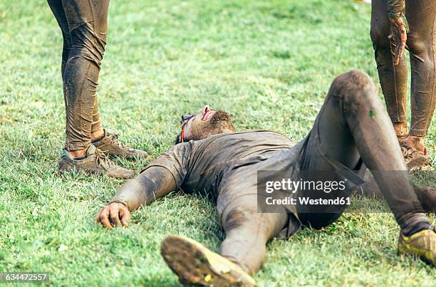participant in extreme obstacle race lying exhaustedly on grass - exhausted runner stock pictures, royalty-free photos & images