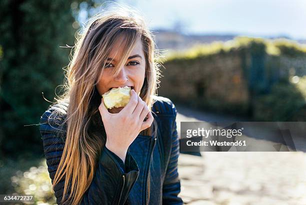 portrait of young women eating apple outside - apple bite out stock pictures, royalty-free photos & images