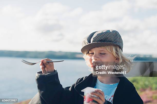france, brittany, atlantic, happy boy at the coast eating yogurt - yogurt stock-fotos und bilder