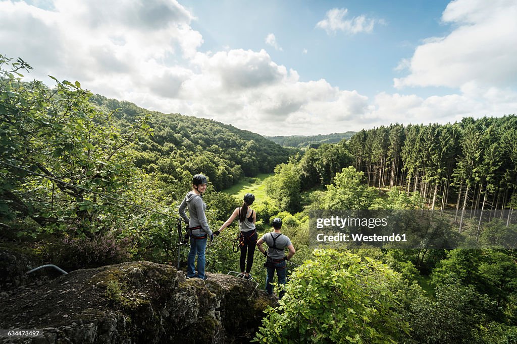 Germany, Westerwald, Hoelderstein, three friends on via ferrata looking at view