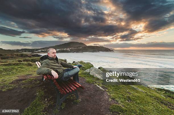 spain, ferrol, man sitting on a bench at the coast looking at distance - ferrol stock pictures, royalty-free photos & images