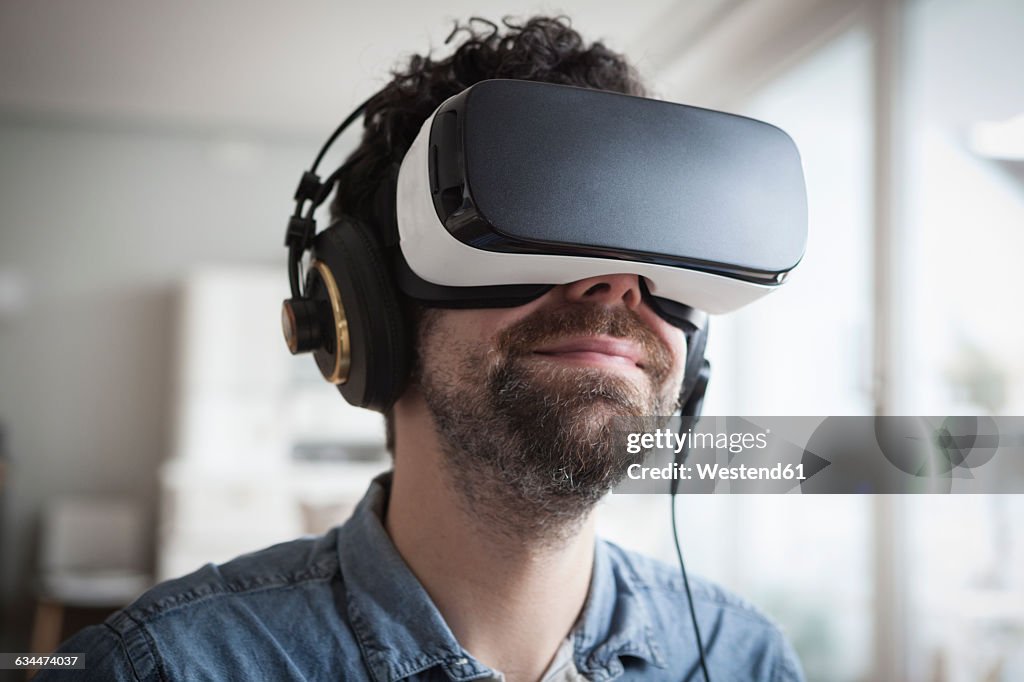 Smiling man wearing Virtual Reality Glasses and headphones