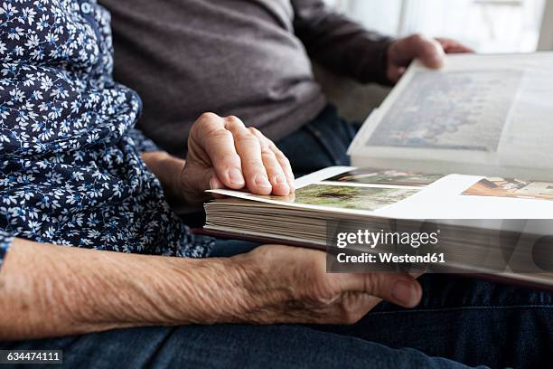 hands of senior couple holding photo album, close-up - album de fotos fotografías e imágenes de stock