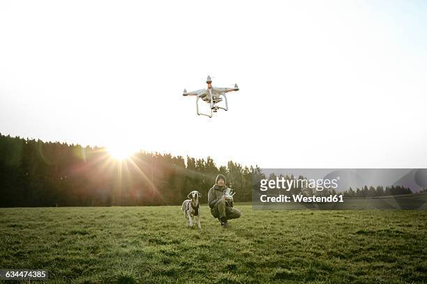 man on a meadow flying drone while his dog watching - flying drone stock-fotos und bilder