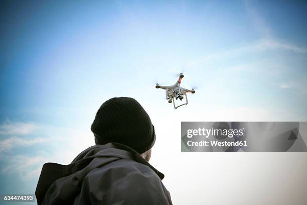 back view of man flying drone - flying drone stock-fotos und bilder