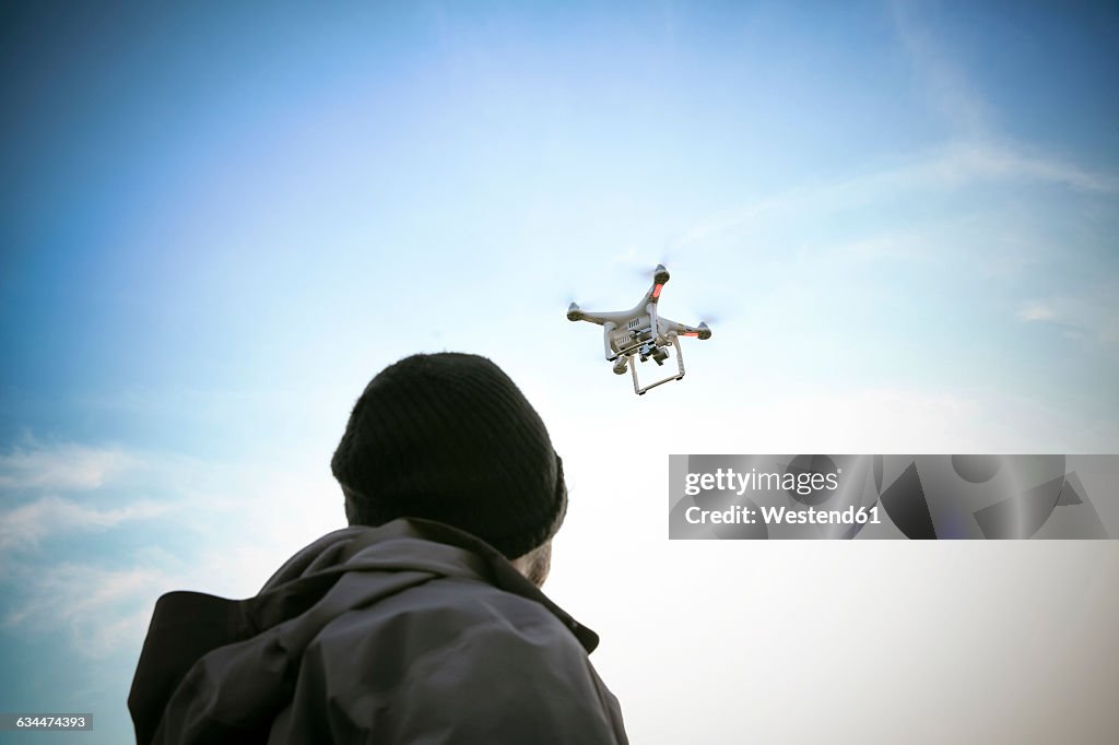 Back view of man flying drone