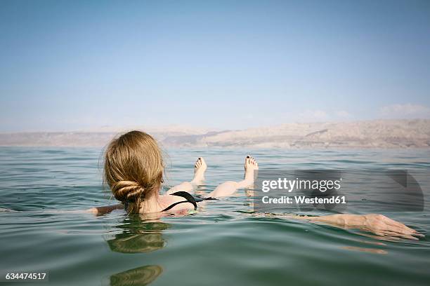 israel, woman floating on water of the dead sea - dead sea foto e immagini stock