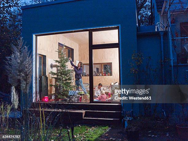 family celebrating christmas at home - homeowners decorate their houses for christmas stockfoto's en -beelden