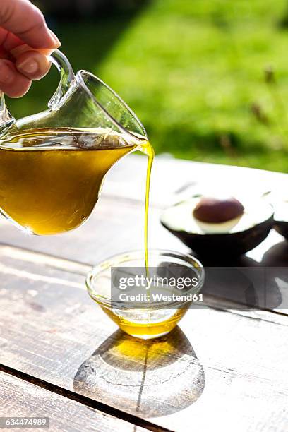 pouring avocado oil into glass bowl - avocado oil stock pictures, royalty-free photos & images